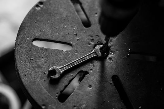 Monochrome image of a spanner on a workbench, highlighting industrial textures.