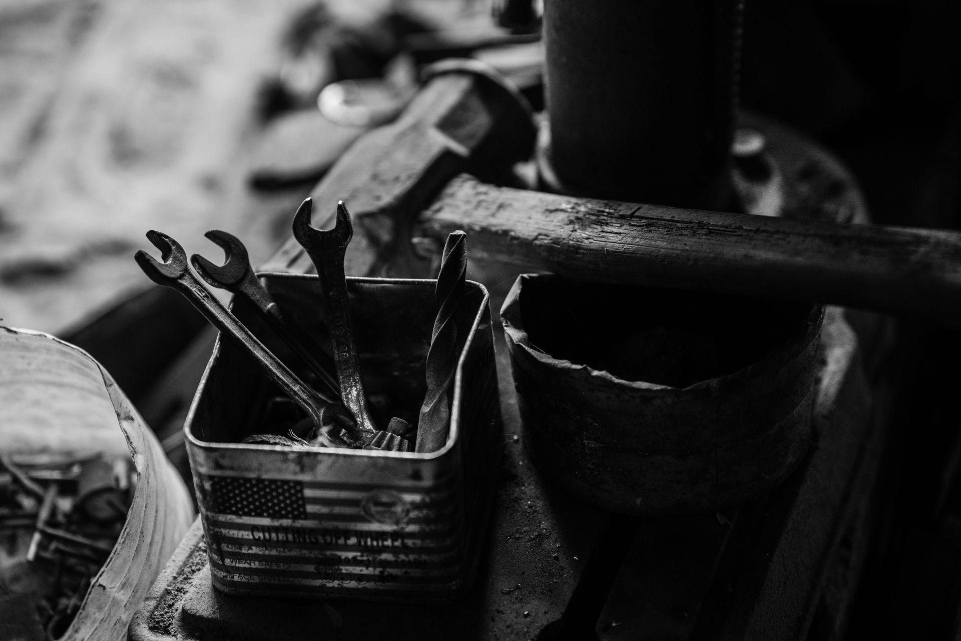 Black and white photo of a rustic workbench with wrenches and tools in a vintage setting.