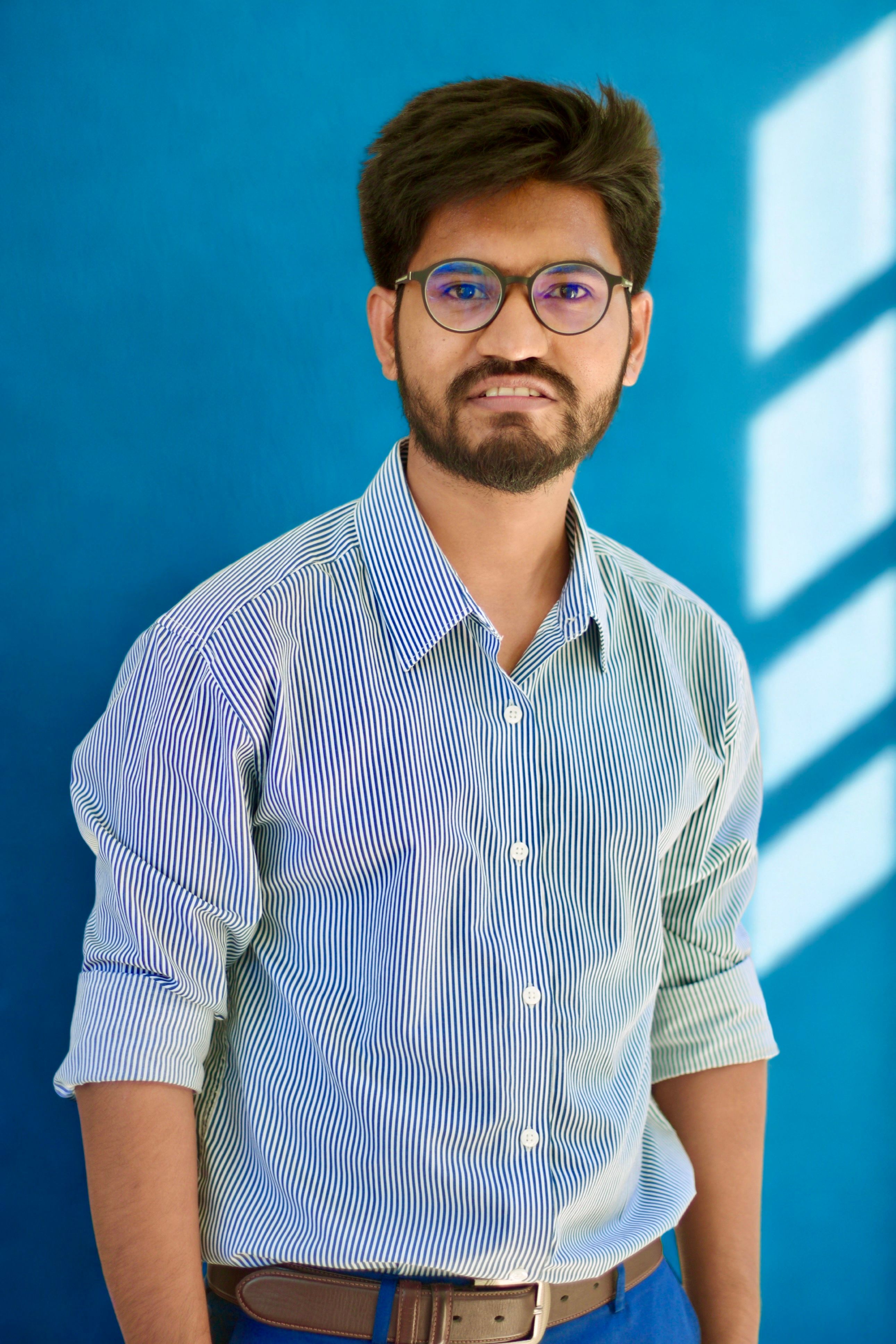 Portrait of a confident young business professional against a light blue background with soft lighting.