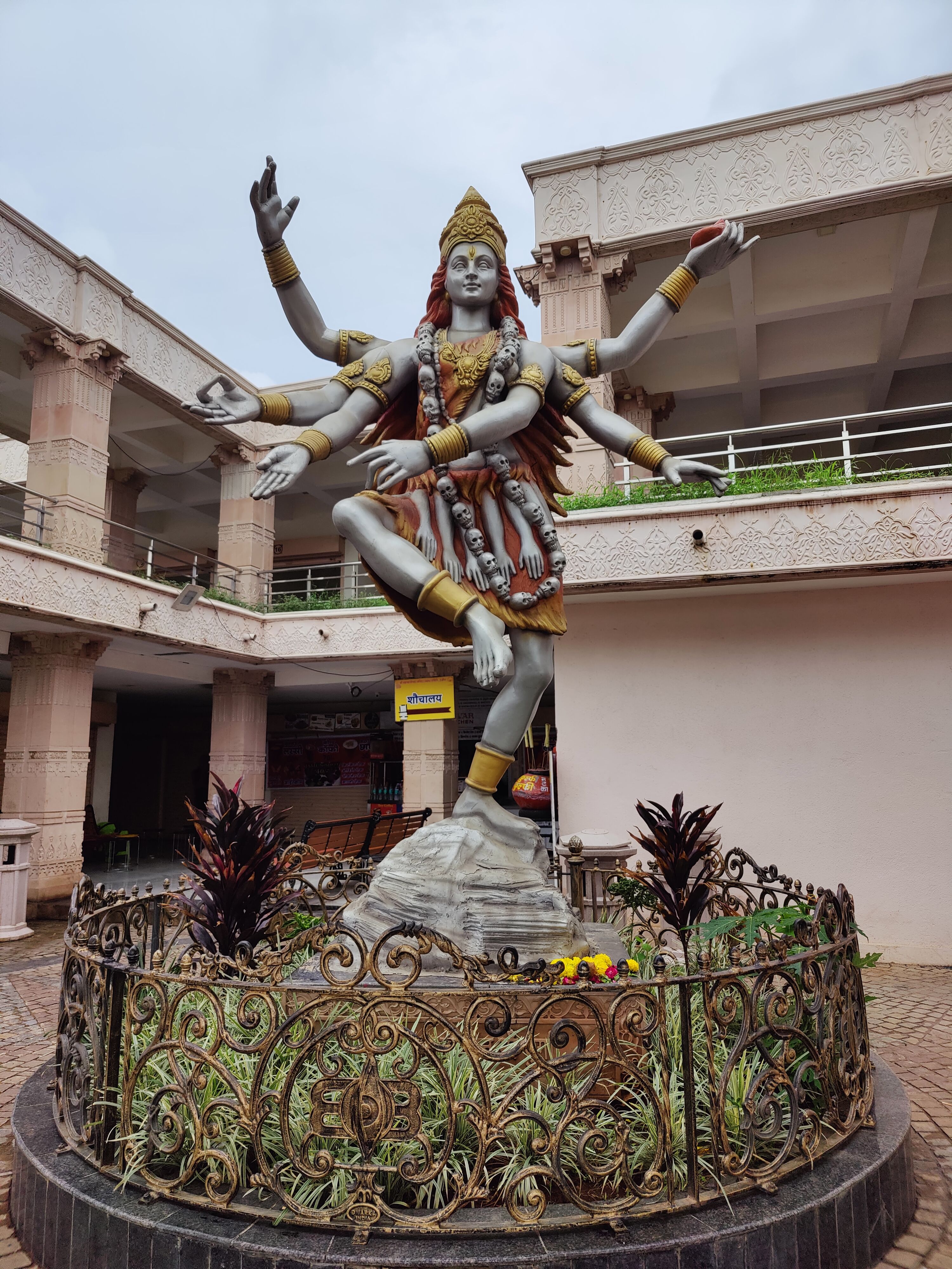 Statue of Lord Shiva with multiple arms in a temple courtyard, showcasing intricate artistry.