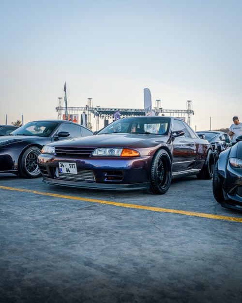 Free Car exhibition in İzmir showcasing iconic Japanese models like the Nissan GT-R under a clear evening sky. Stock Photo