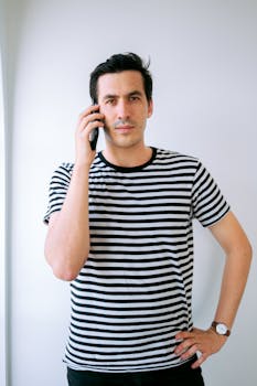 Portrait of a man in a striped shirt talking on his phone indoors.