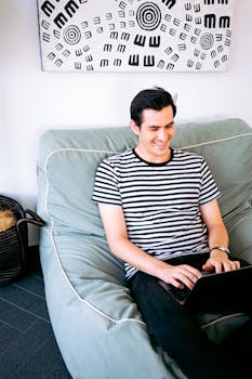 男人在室内用笔记本电脑随意工作，体现了远程办公的舒适性