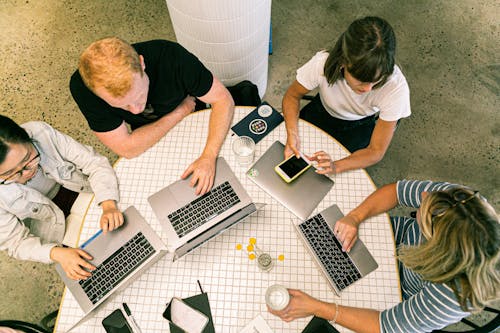 Free Four People Using Laptop Computers and Smartphone Stock Photo