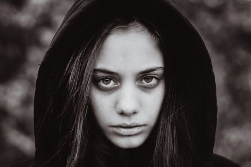 Free Stunning black and white portrait capturing the intense gaze of a woman wearing a hood. Stock Photo