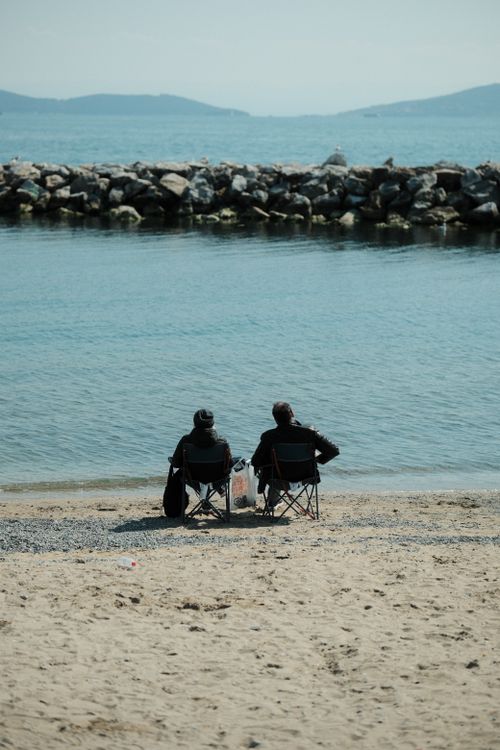 Free Two adults relax on a peaceful beach in Degirmendere, Kocaeli, Türkiye, enjoying the tranquil sea view. Stock Photo