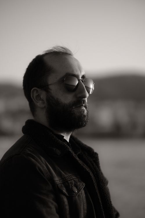 Free A man in sunglasses and jacket looking pensive during sunset outdoors. Stock Photo