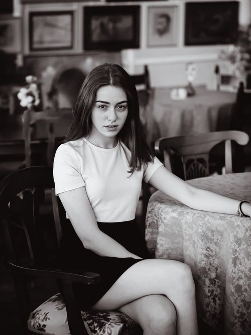 Free Black and white portrait of a woman in a vintage-styled cafe, exuding classic elegance. Stock Photo