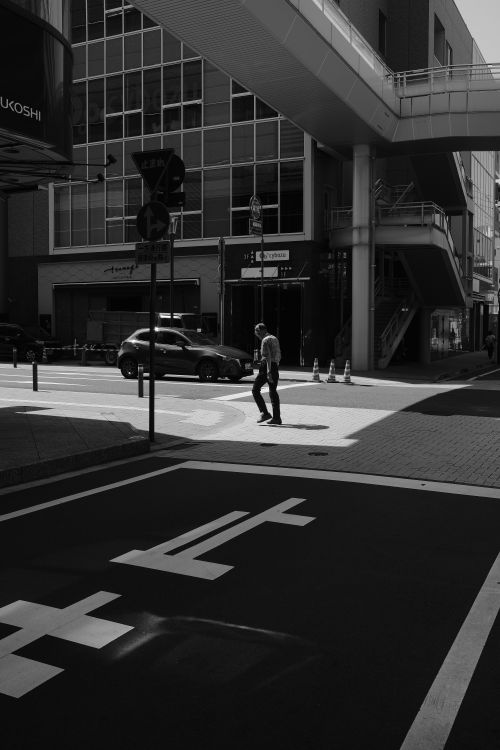 Free A person crossing a city street in a dramatic black and white setting. Stock Photo