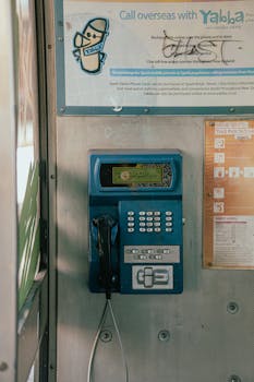 A retro blue payphone stall located in Whanganui, featuring informational posters and signs.