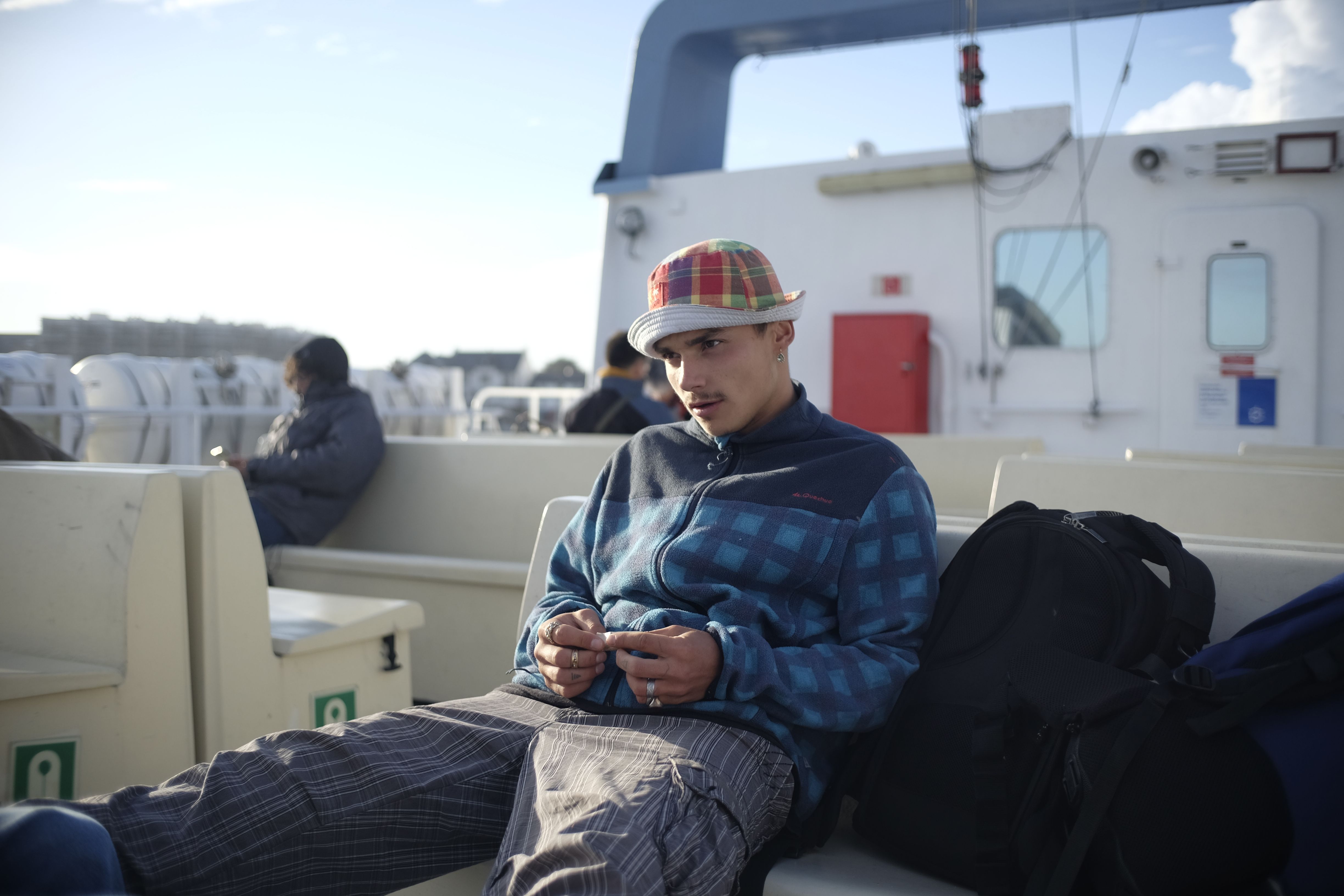 Casual young man relaxing on ferry deck, enjoying a leisurely journey at sea.