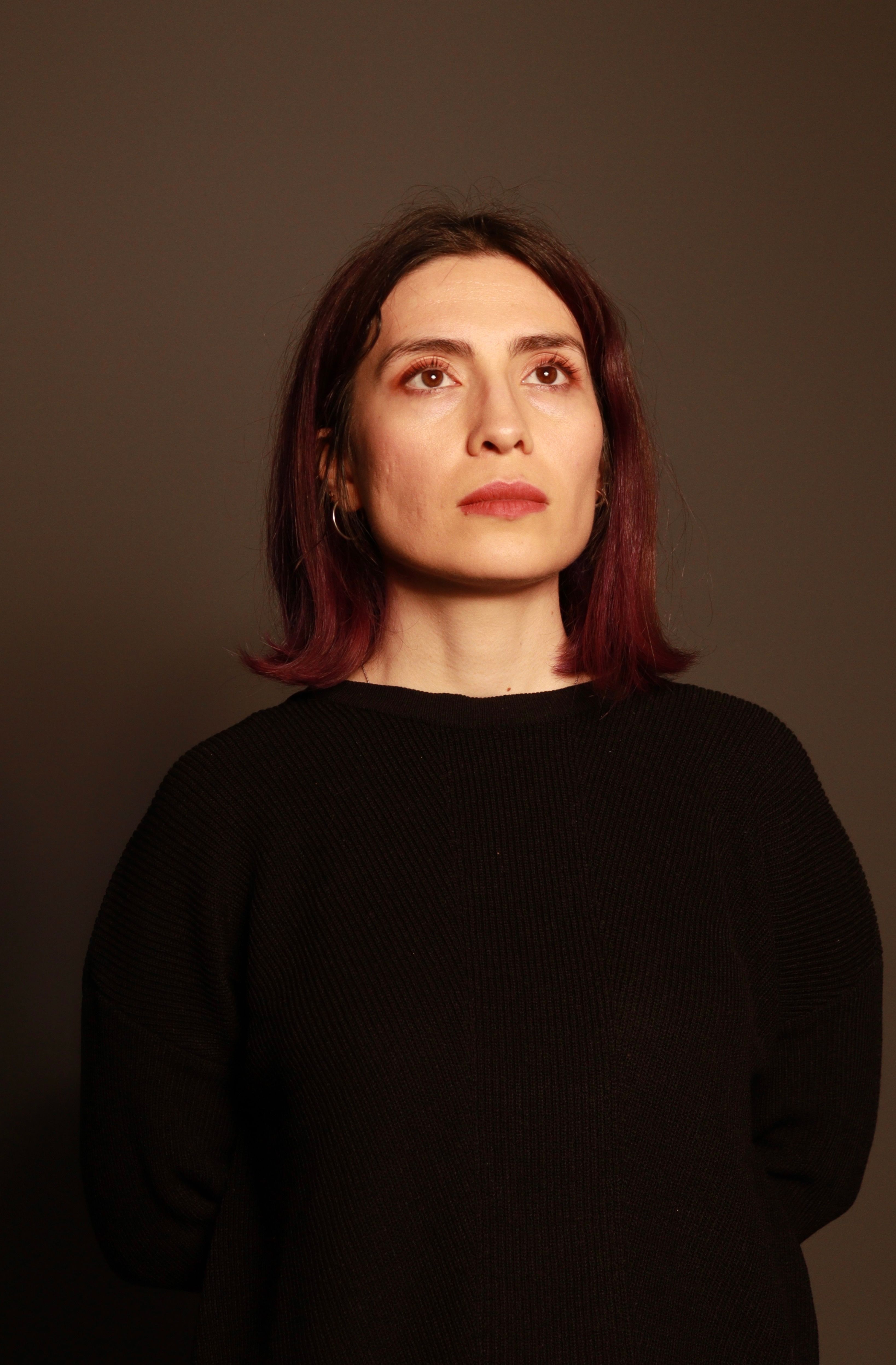 Portrait of a woman in dramatic lighting, showcasing thoughtful expression and warm tones.
