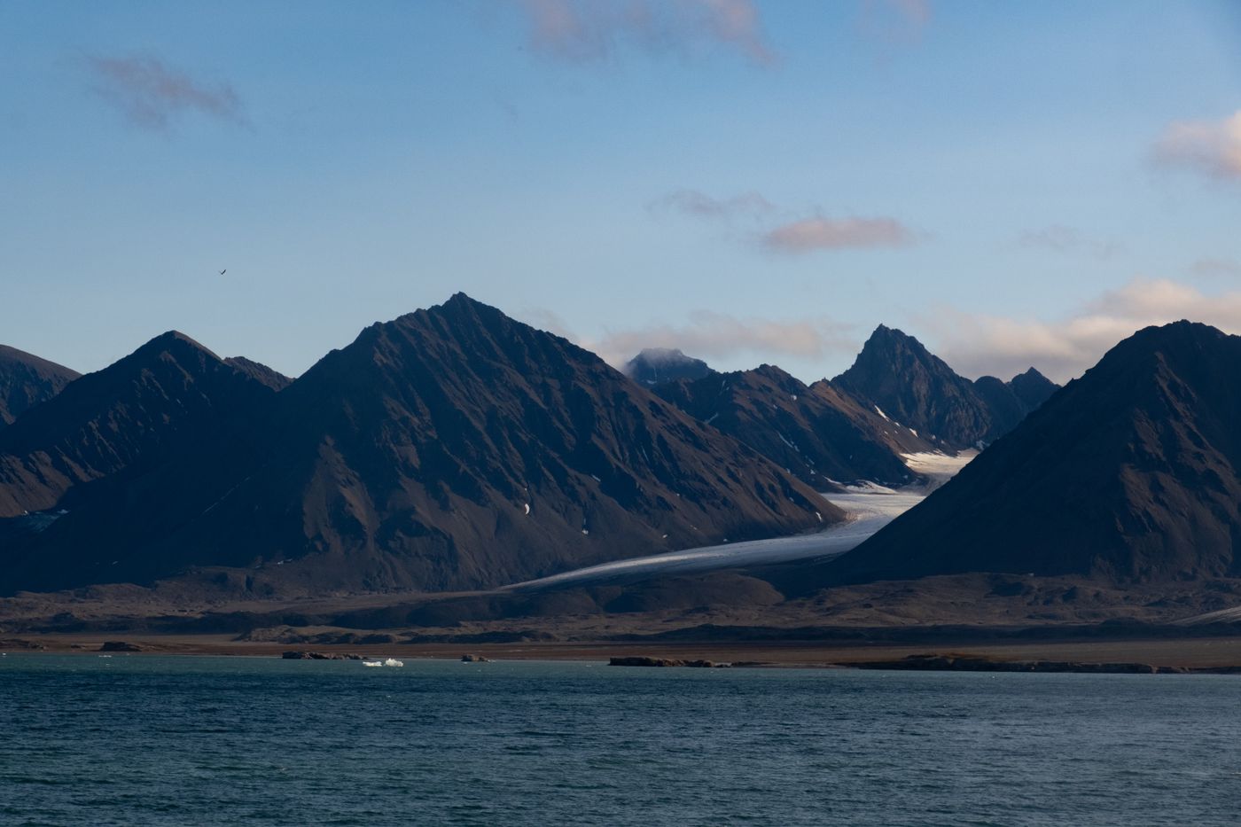 A mountain range with a glacier meeting Arctic water under a clear sky, Svalbard