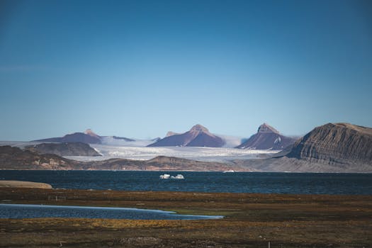Scenic view of arctic mountains and glacier under a clear blue sky.