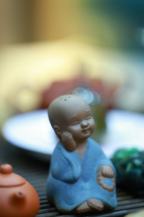 Free A tranquil ceramic monk figurine in blue robe placed on a wooden table. Perfect for zen-themed designs. Stock Photo
