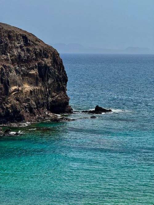 Free Captivating view of Lanzarote's rocky cliff and turquoise ocean, offering a serene and scenic landscape. Stock Photo