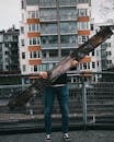 Person in Blue Denim Jeans Standing Holding Brown Wooden Log