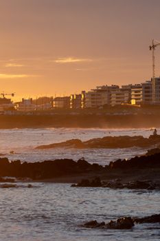 Captivating sunset at Punta del Este beach with rocky shores and city skyline in Uruguay.
