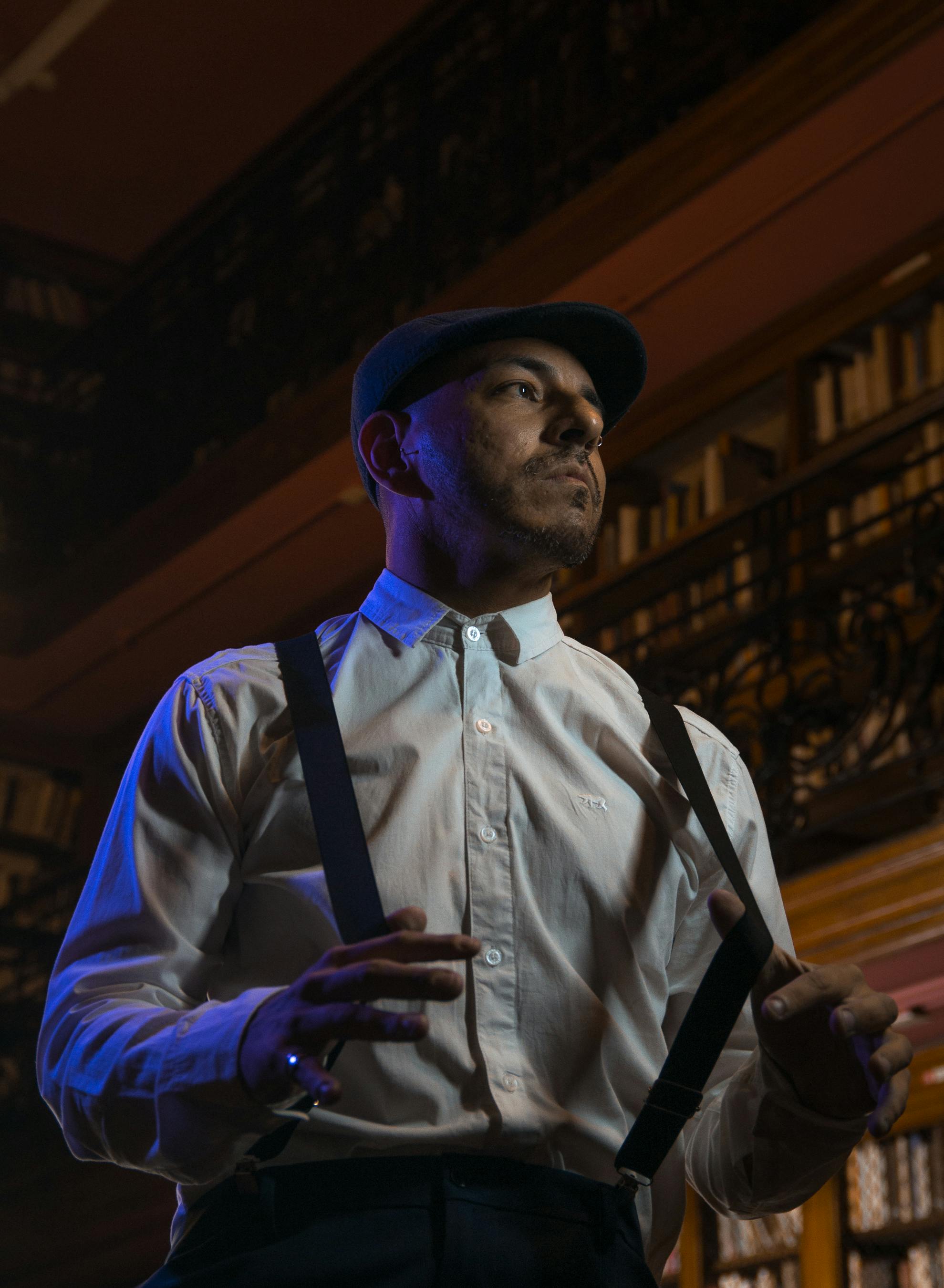 Ücretsiz Vintage kıyafetler içindeki adam, loş ışıklı bir kütüphanede kendinden emin bir şekilde poz veriyor ve klasik bir hava yaratıyor. Stok Fotoğraflar