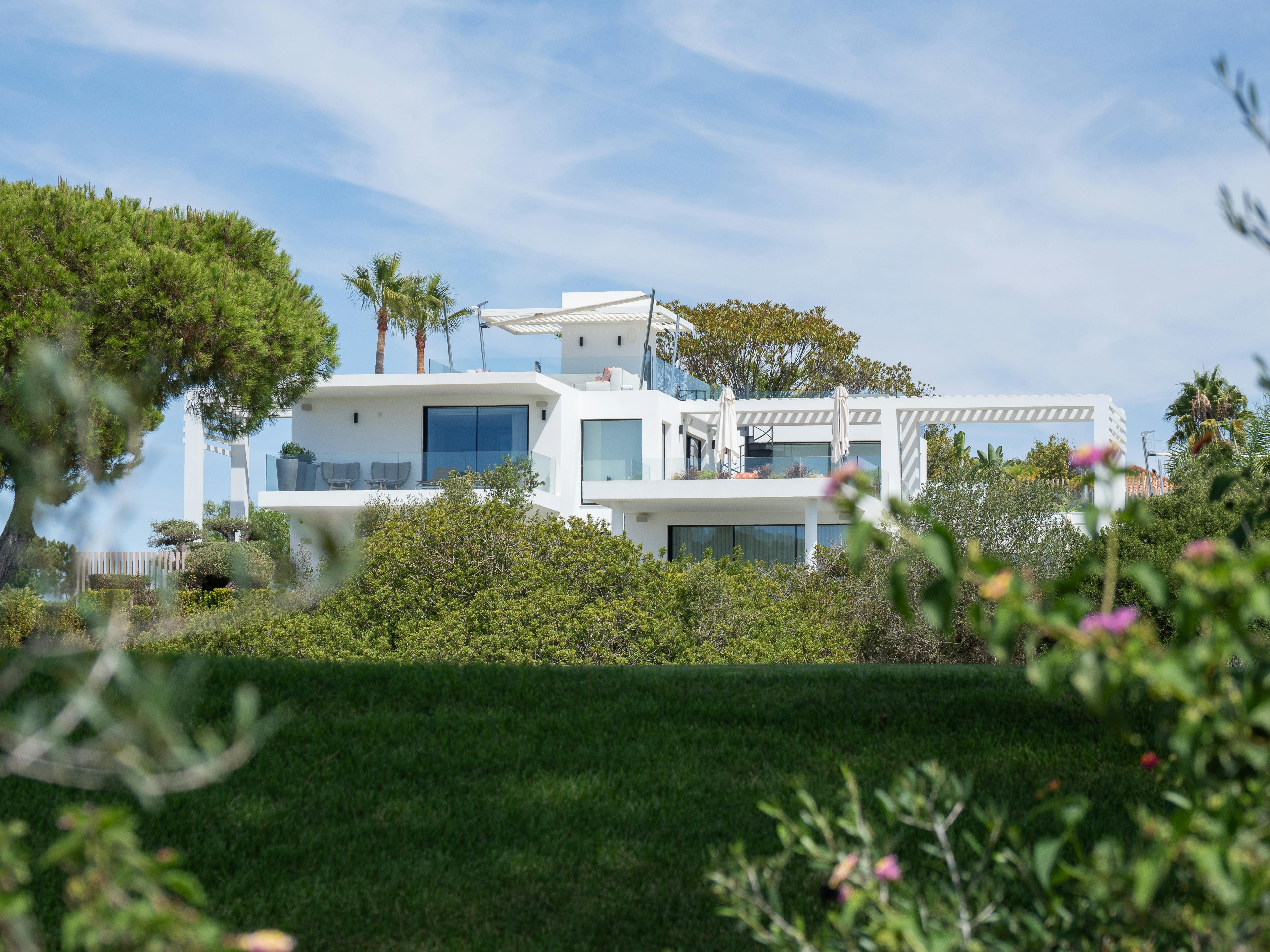 Stunning modern white villa surrounded by lush greenery in Faro, Portugal.