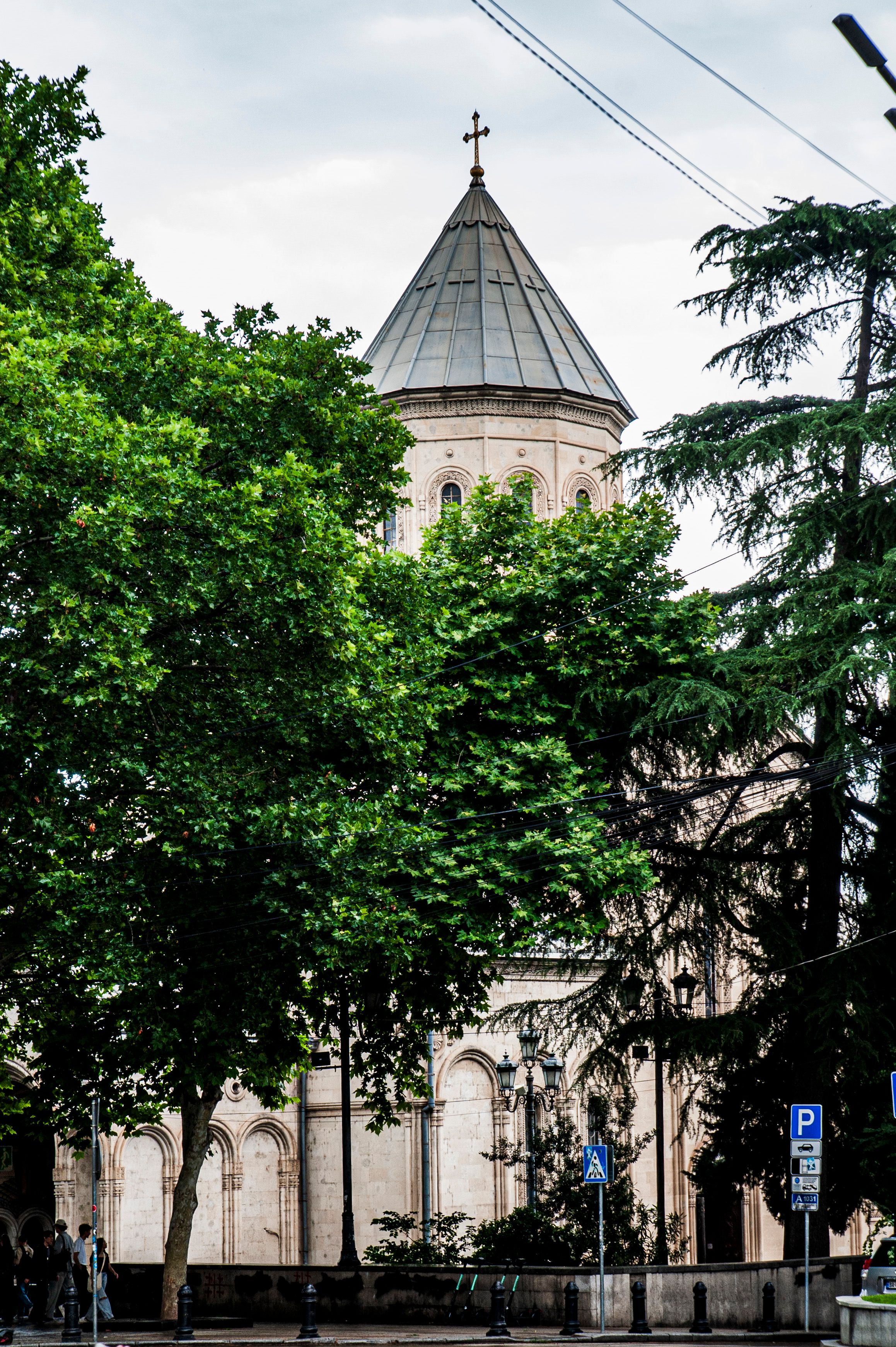 A view of St. George Cathedral dome surrounded by lush trees in Tbilisi, Georgia.