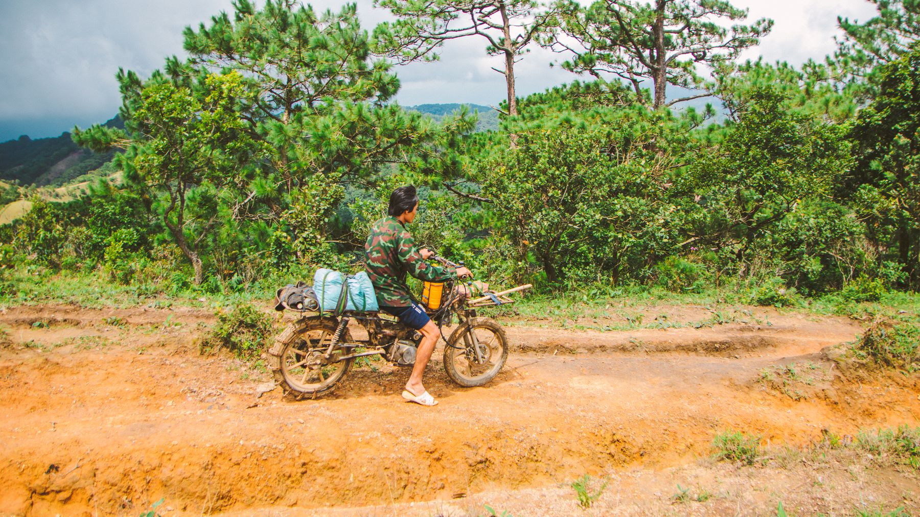 A man riding a motorcycle through scenic countryside in Lâm Đồng, Vietnam.