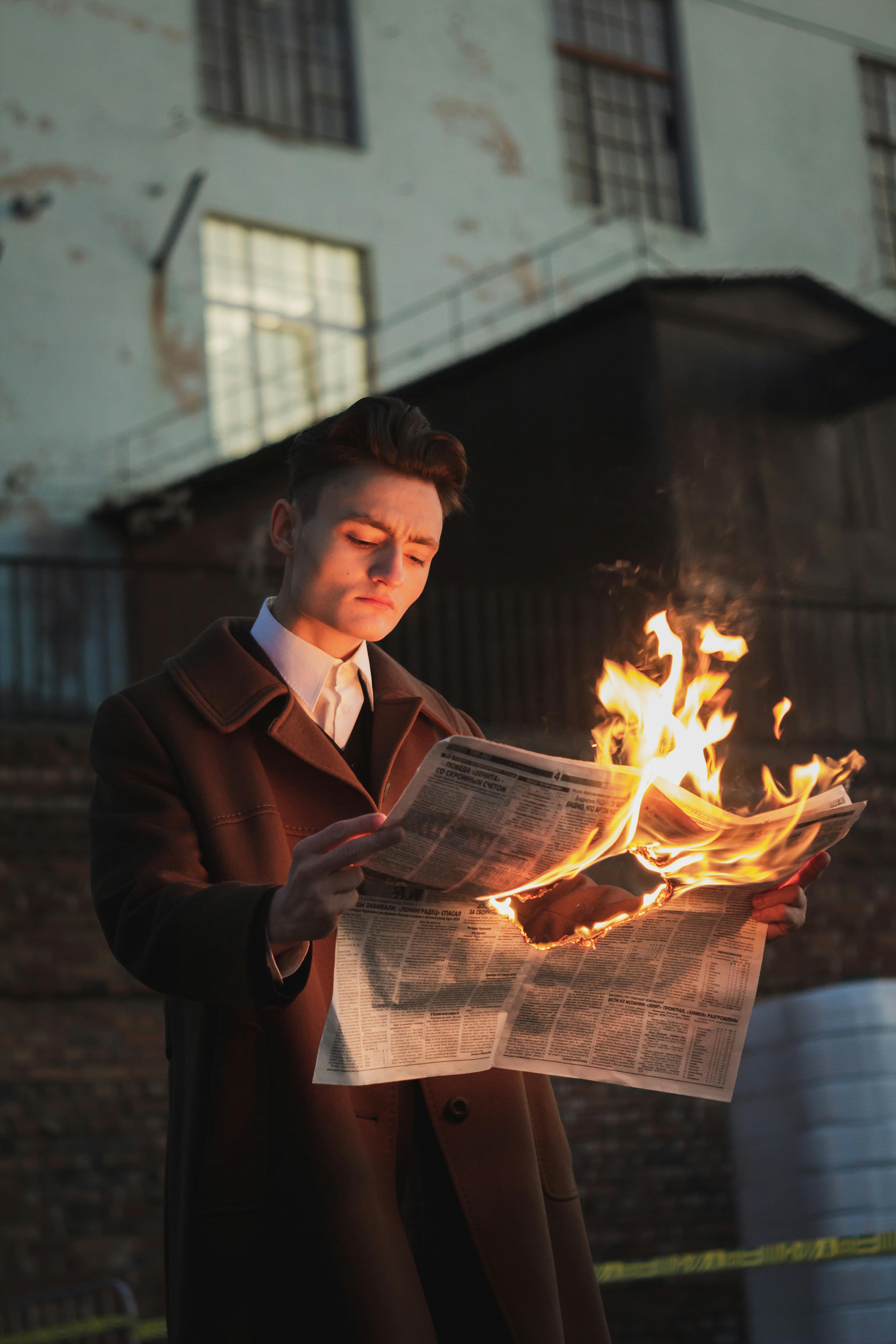 man reading burning newspaper