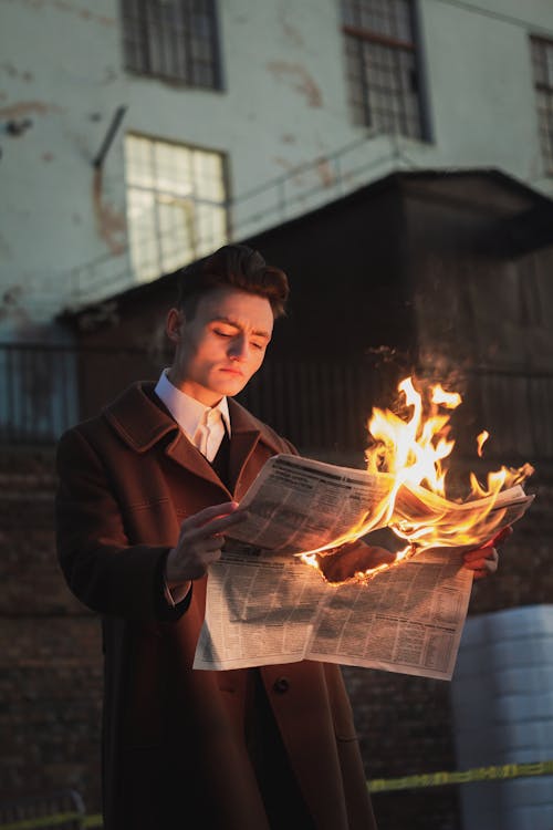 young man reading a burning newspaper