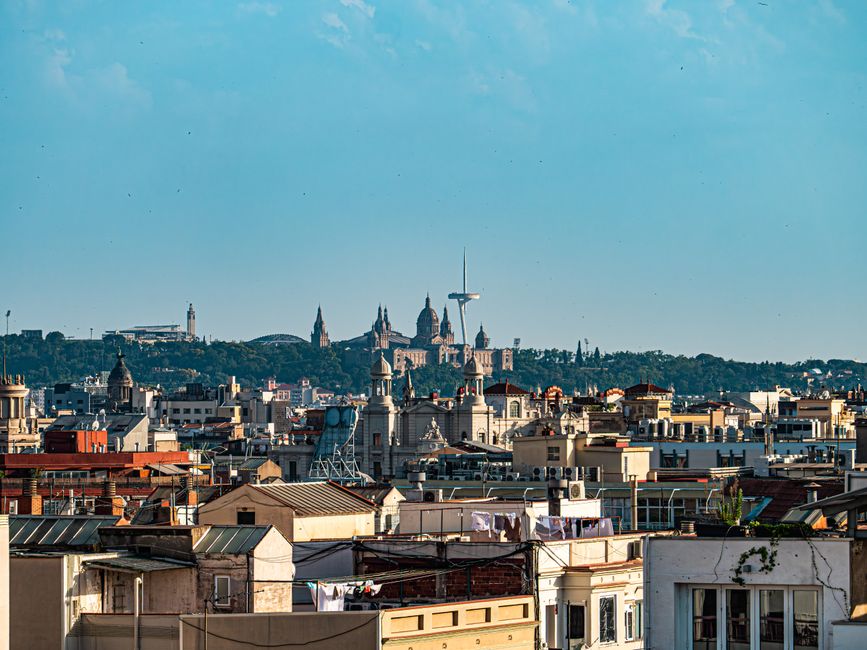 Vista panorámica del horizonte de Barcelona con los monumentos emblemáticos de Montjuïc bajo un cielo azul brillante.