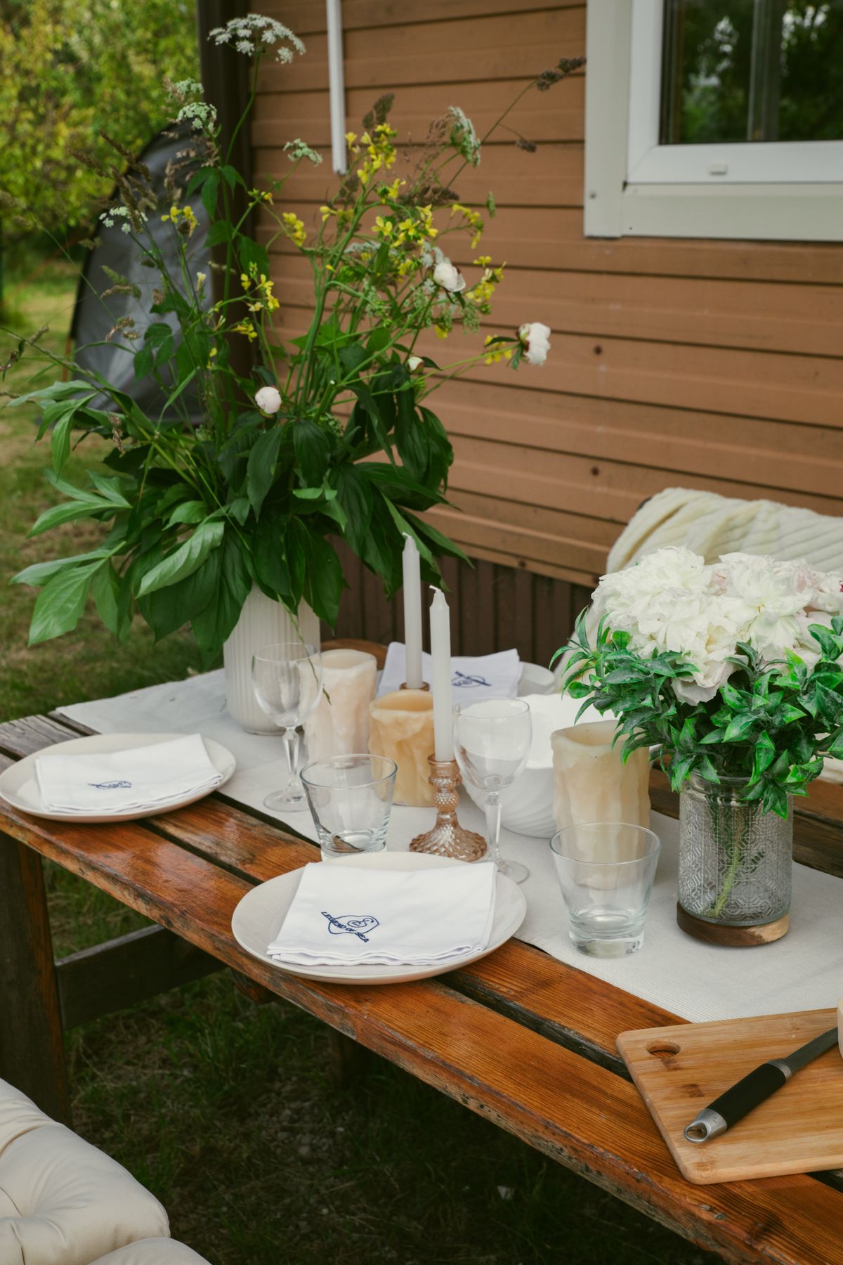 Rustic outdoor table setup with flowers, ideal for a cozy gathering. Stock Photo.