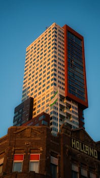 A contemporary high-rise building in Rotterdam during sunset.