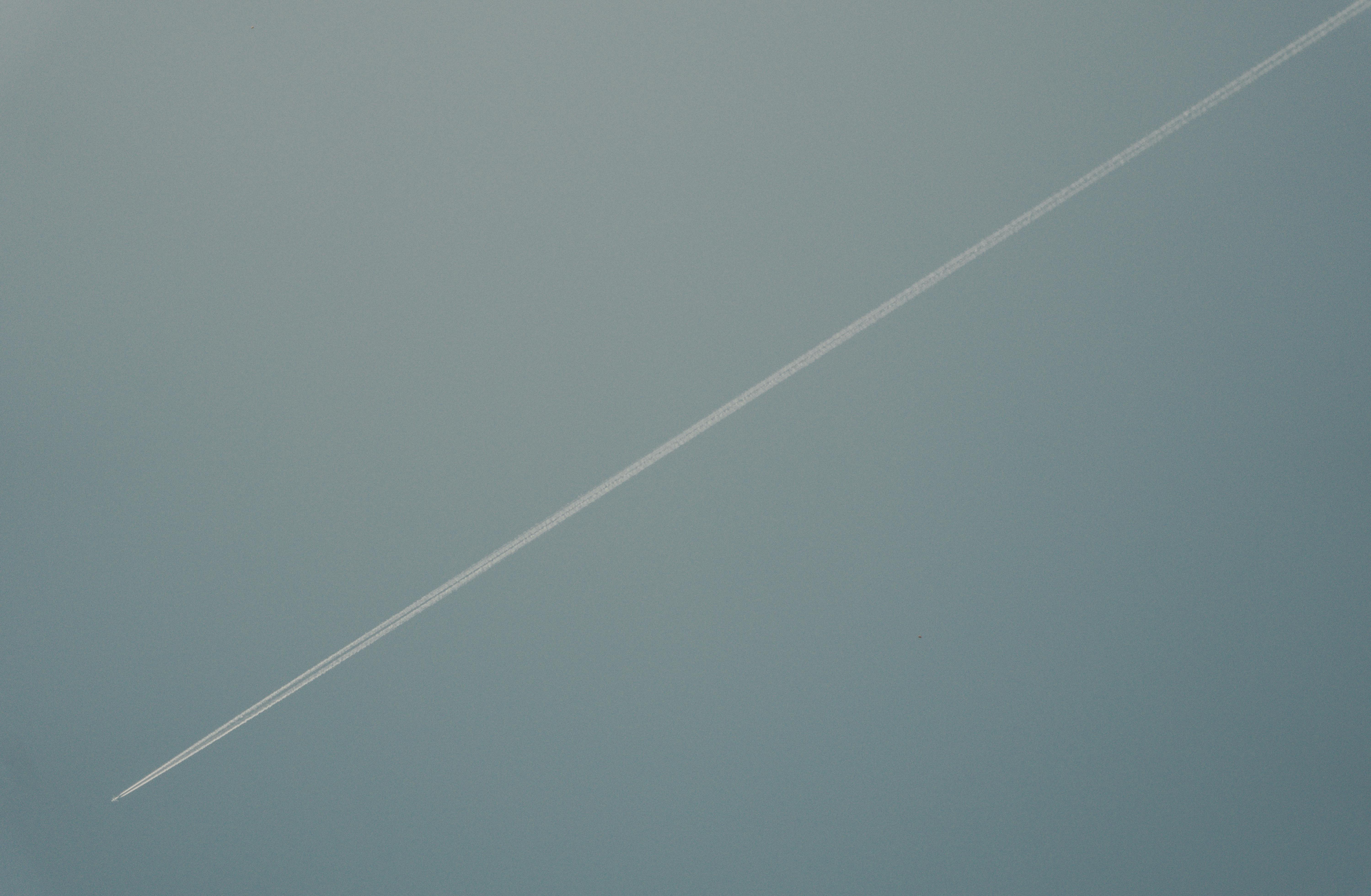 bezplatná Bílá kondenzační stopa diagonálně se táhne po jasné modré obloze a symbolizuje let a cestování. Základová fotografie