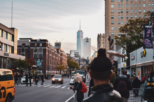 Vibrant street scene in NYC featuring One World Trade Center at sunset.