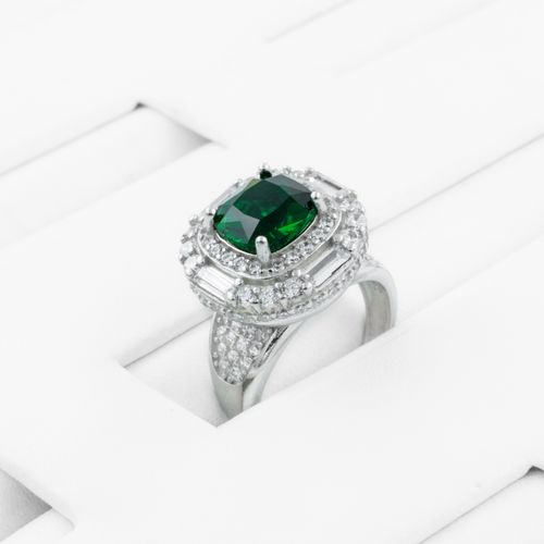 Free Stunning silver ring featuring an emerald-like green gemstone surrounded by diamonds on a white background. Stock Photo
