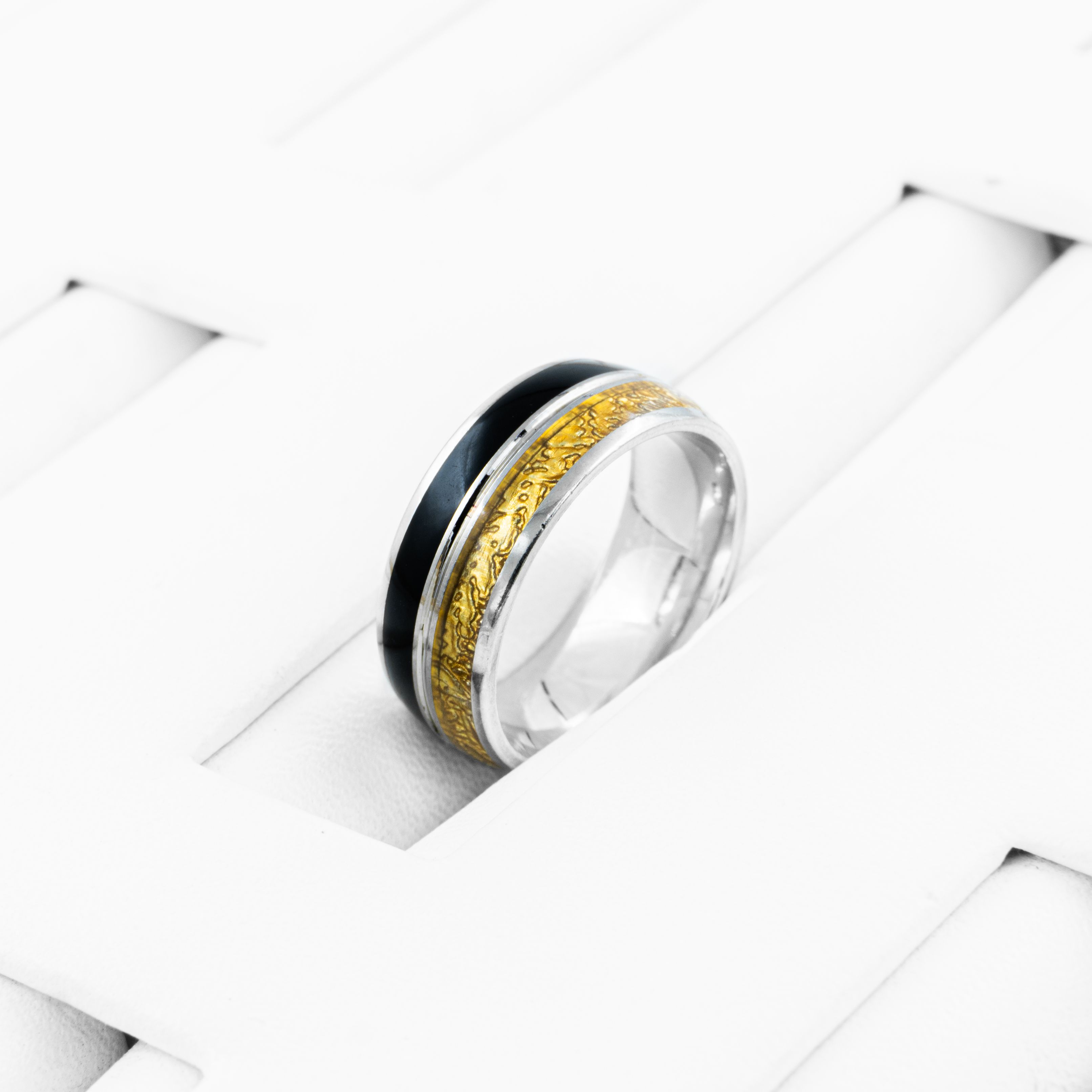 Close-up of a stylish ring with gold and black inlays on a modern white background.