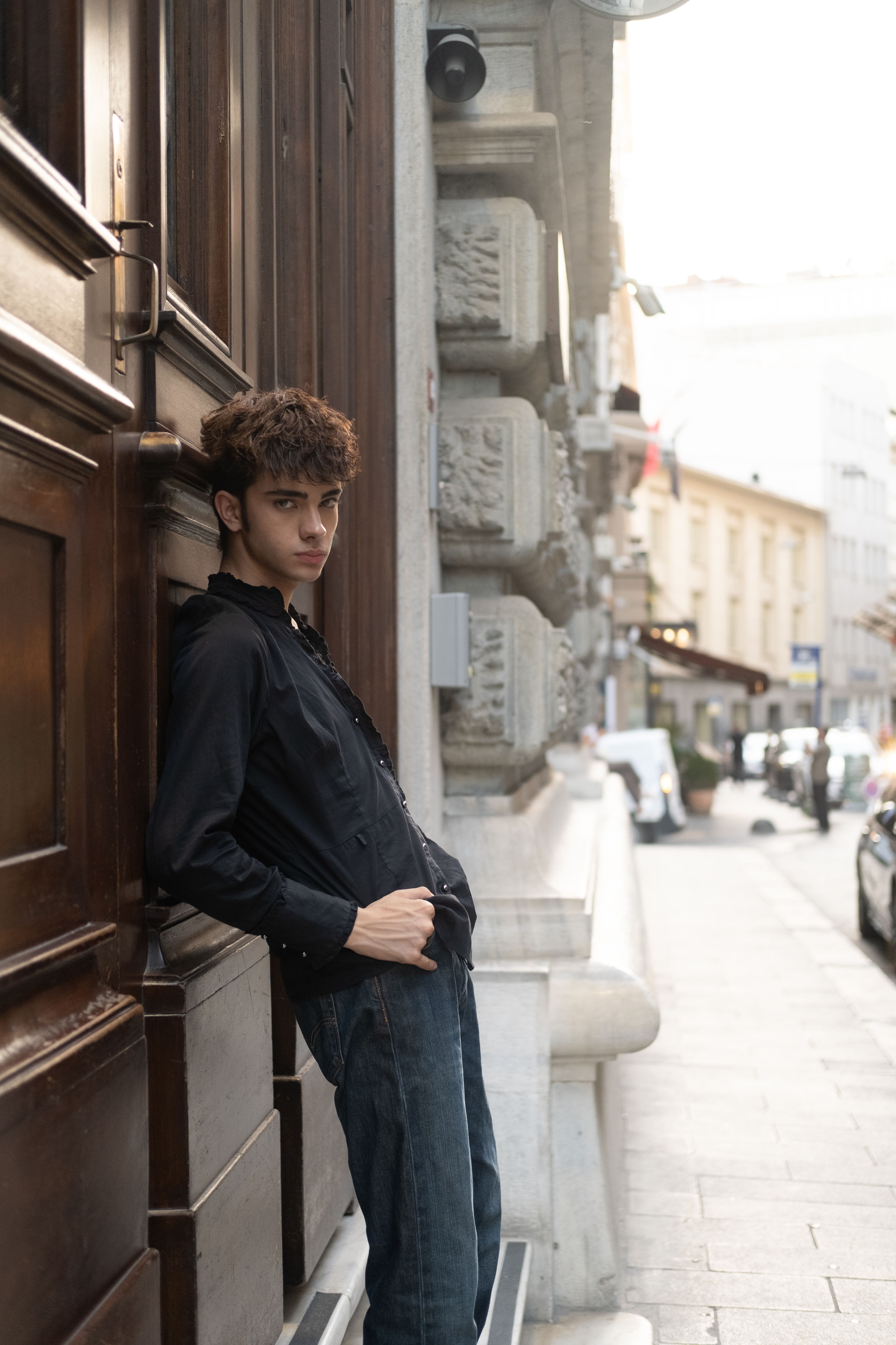 Young man in a black shirt leaning against a building in Istanbul's bustling street, capturing urban vibes.