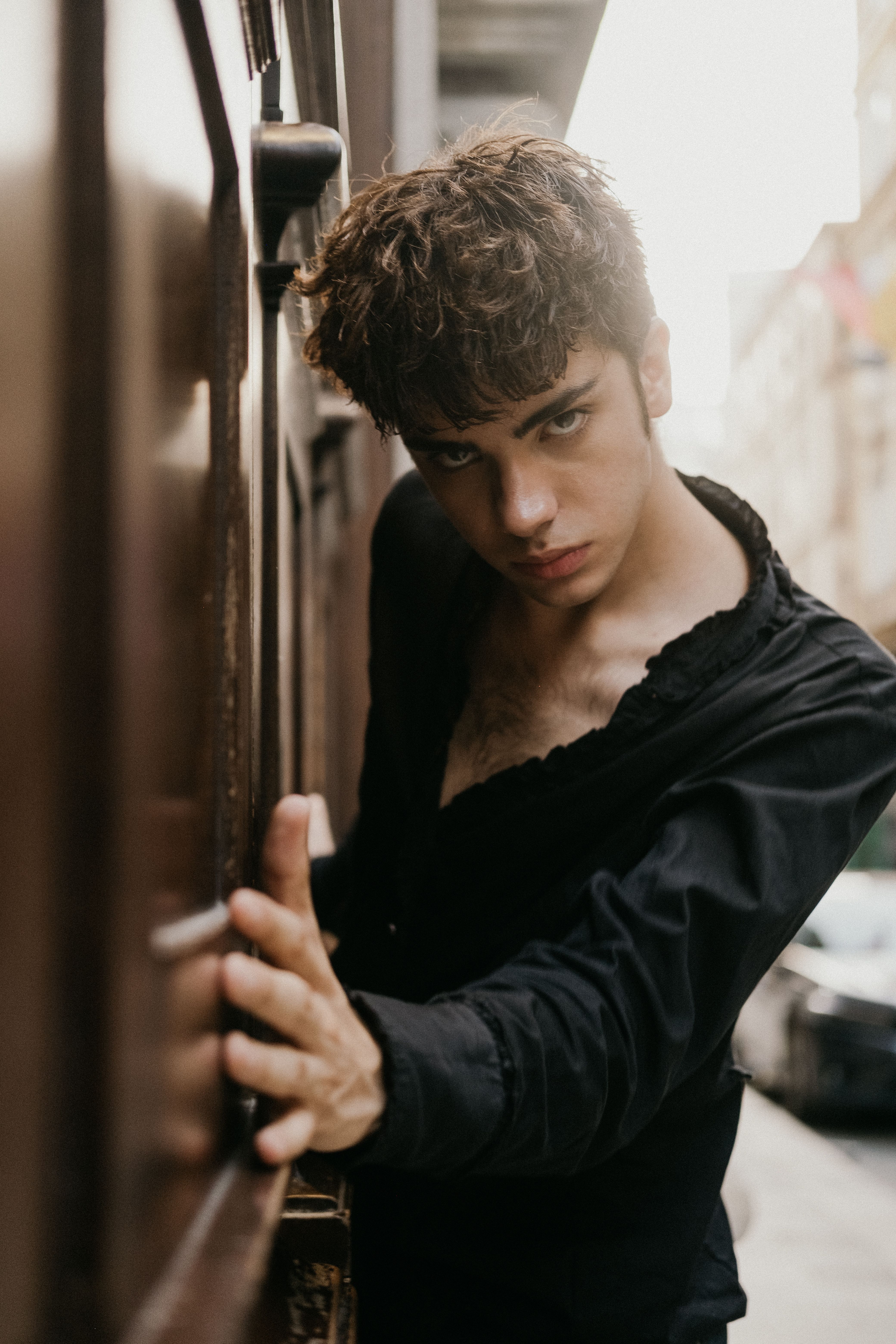 Portrait of a young man in a black shirt leaning against a wall on a street in Istanbul, Türkiye.