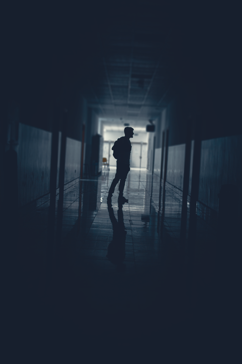Free Silhouetted figure in a dimly lit hallway creates an eerie and solitary atmosphere. Stock Photo