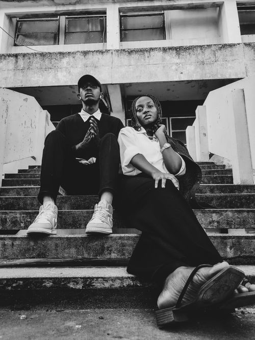 Free Artistic black and white portrait featuring two young adults sitting on urban steps. Stock Photo