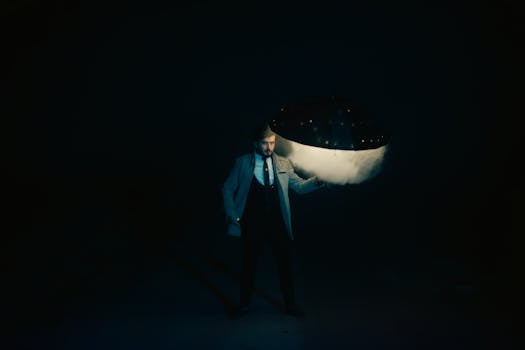 A man in a suit holding an illuminated umbrella in a dark setting, exuding mystery and style.
