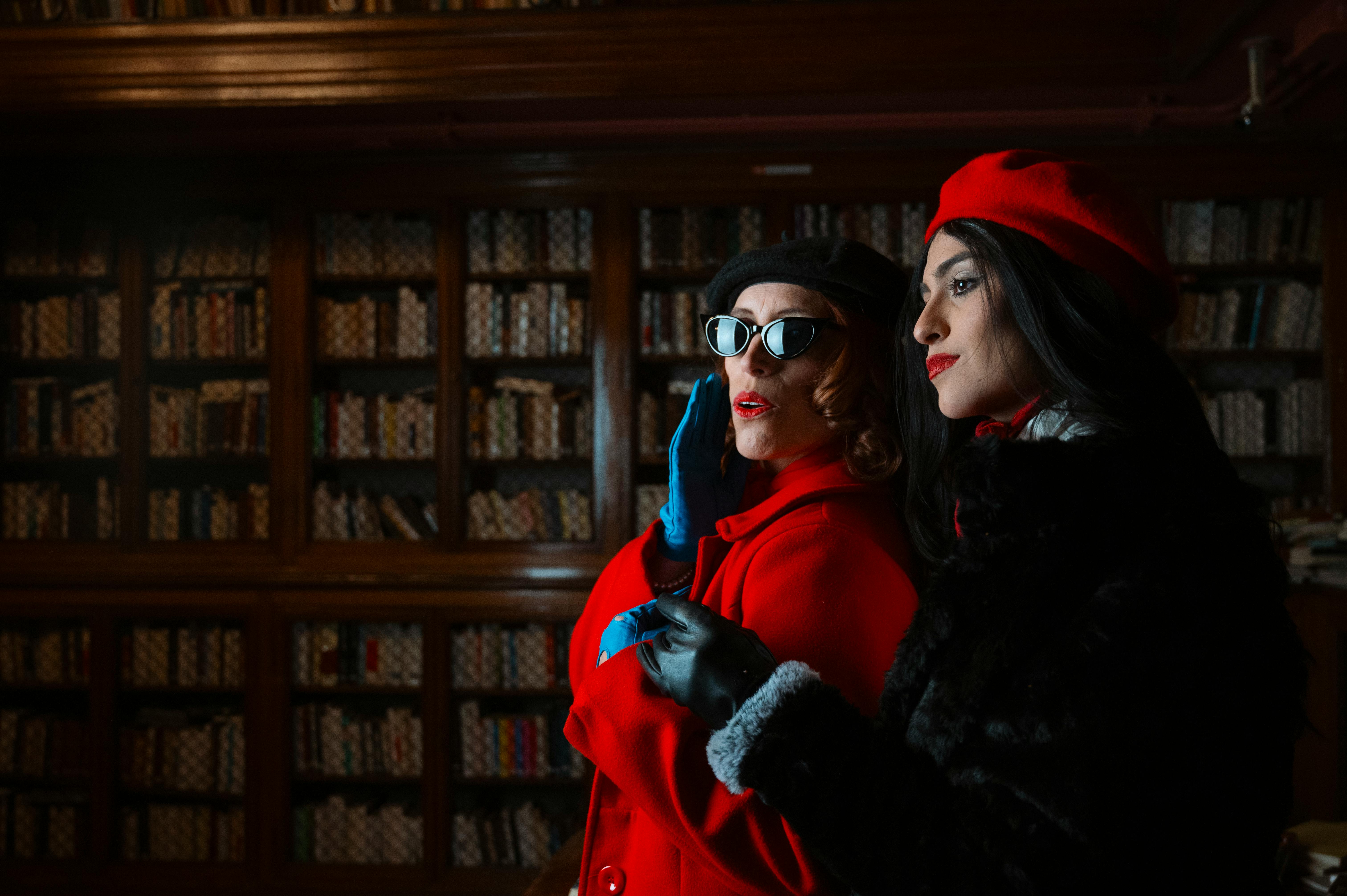 Gratuit Două femei la modă într-o bibliotecă, purtând ținute retro și pozând dramatic. Fotografie de stoc