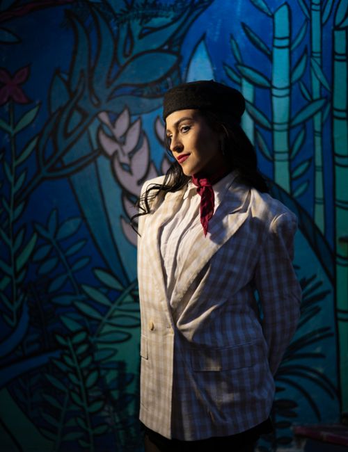 Free Portrait of a stylish woman in a vintage outfit against a vibrant mural backdrop, offering an artistic vibe. Stock Photo