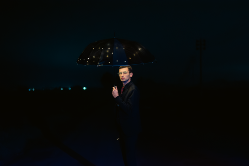 Free Elegant nighttime portrait of a man holding an illuminated umbrella, exuding charm and style. Stock Photo