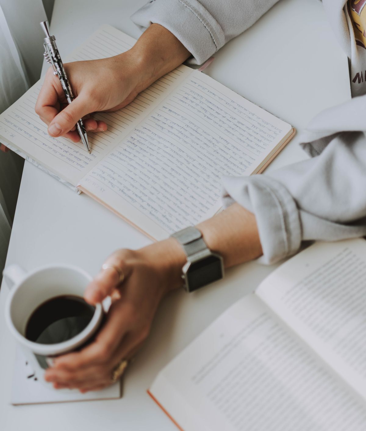 Writing a brain dump in a notebook next to a coffee, clearing mental clutter to reduce time pressure