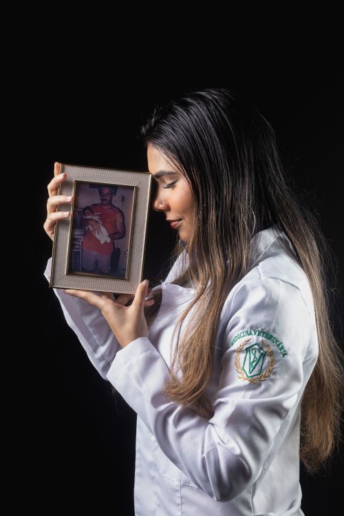 Free Young female veterinarian in white coat holding a nostalgic photo frame with warmth. Stock Photo