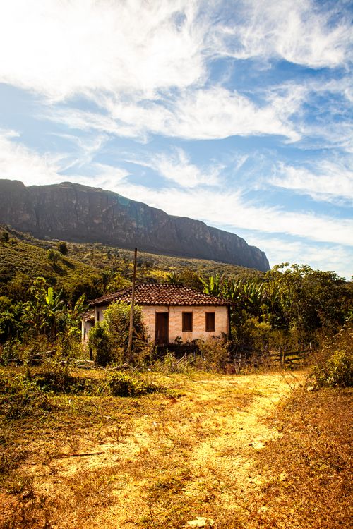 Free Abandoned rustic house with a scenic mountain backdrop under a bright blue sky. Stock Photo
