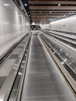 Empty moving walkway inside a modern airport terminal, showcasing sleek design and bright lighting