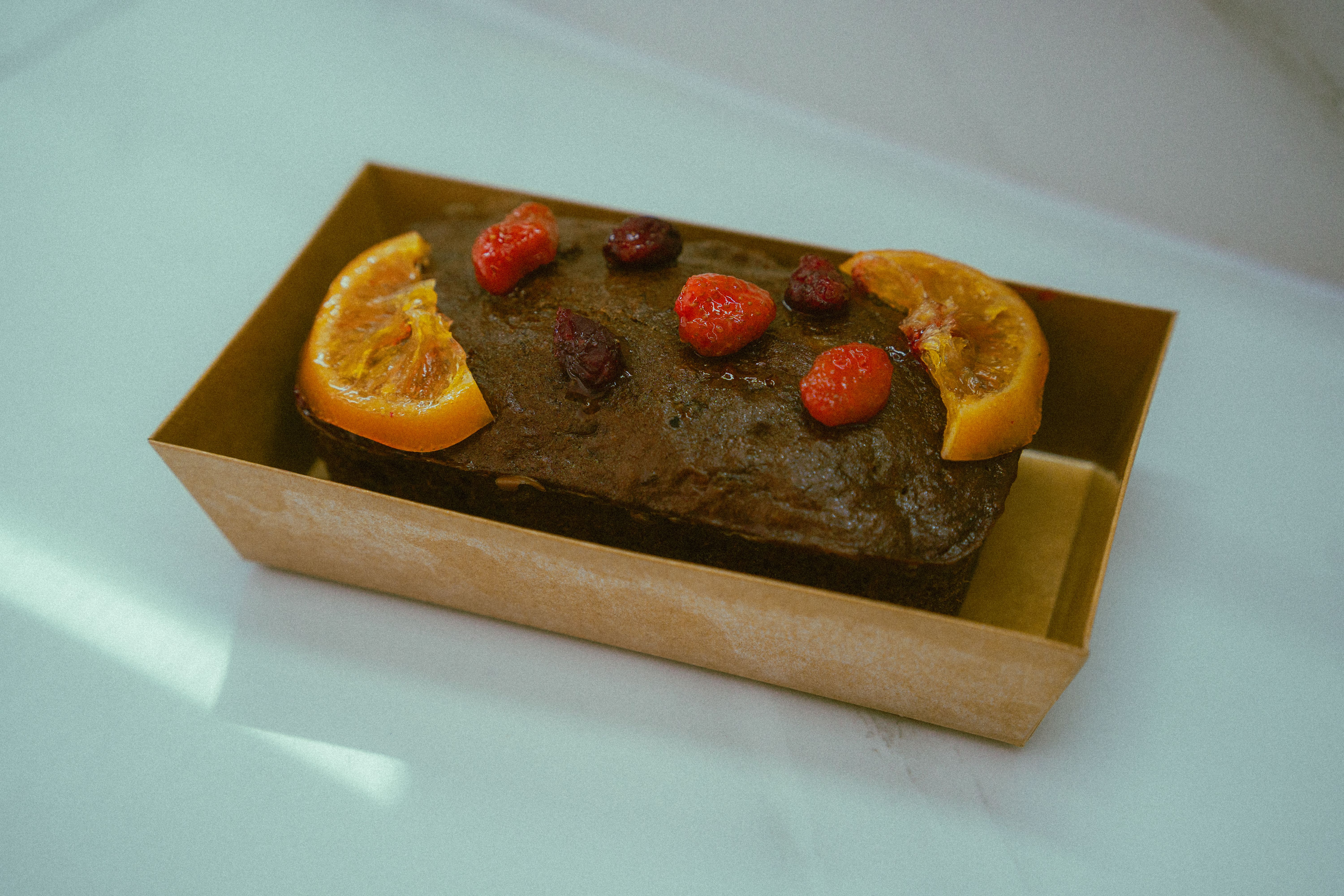 A beautifully presented chocolate fruitcake garnished with fresh oranges and berries in Ho Chi Minh City.