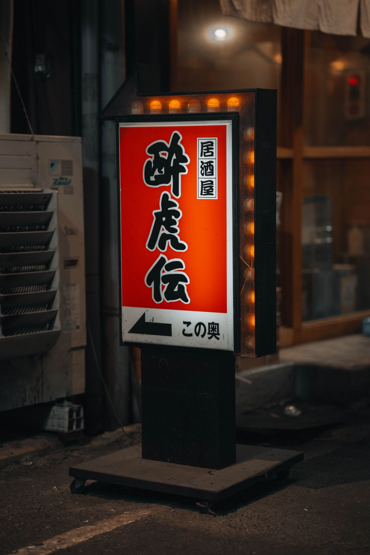 An illuminated izakaya sign glowing on a dark Japanese street