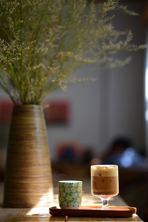 Free A serene café setting showcasing an iced coffee and a vase on a wooden table. Stock Photo
